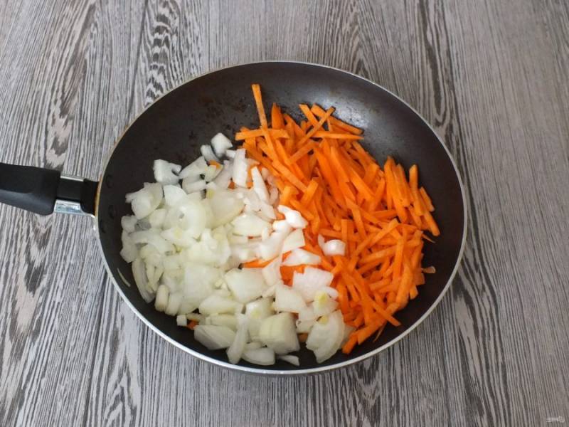 В сковороду, где обжаривалось мясо, налейте растительное масло. Переложите лук и морковь. Обжарьте до полуготовности.