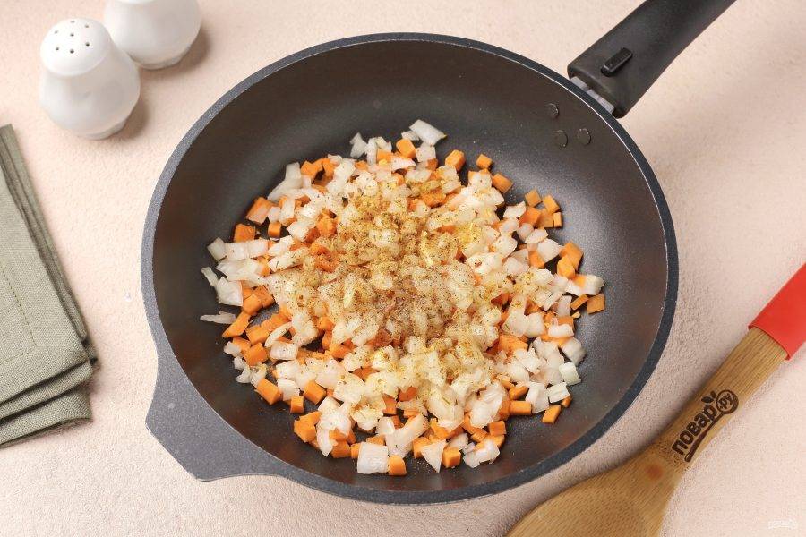 В сковороде разогрейте масло, выложите нарезанные кубиками лук и морковь. Добавьте специи по вкусу.