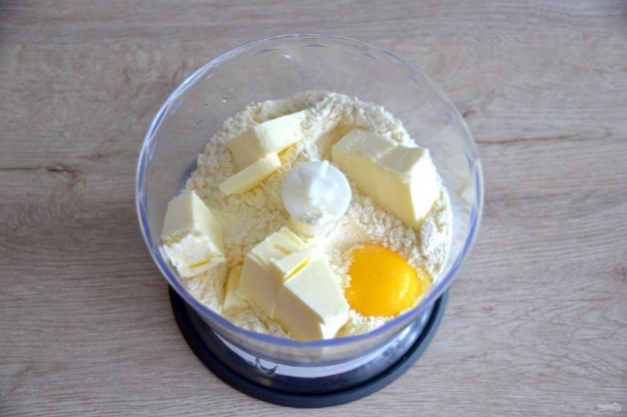 Вернемся к процессу приготовления печенья с марципаном. Всыпьте в блендер муку, 50 грамм сахарной пудры, соль, добавьте нарезанное кубиком холодное сливочное масло, добавьте один яичный желток. Пробейте в крошку. 