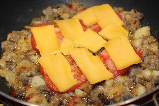 Выложите наверх помидоры и сыр. Накройте крышкой и готовьте на медленном огне, пока сыр не расплавится.