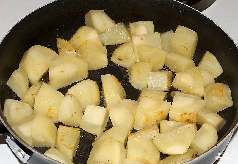 3. Очистите картофель и нарежьте такими же кубиками. Выложите на отдельную сковороду с маслом и обжарьте на сильном огне. 