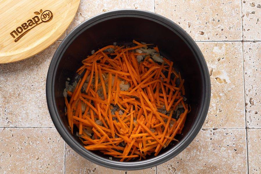 Морковь натрите на терке и добавьте в мультиварку. Жарьте еще несколько минут, пока морковь не станет мягче и не приобретет золотистый цвет.