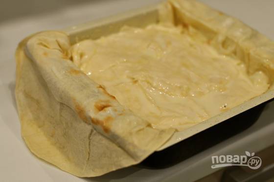 Далее всыпьте часть сыра. Другой лаваш нарвите средними кусочками. Каждый окуните в кефирную смесь, а потом несколькими закройте сыр.