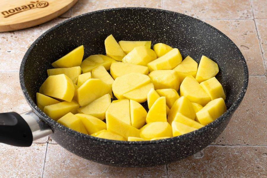 Картофель помойте, очистите от кожуры и нарежьте крупными ломтиками. Разогрейте сковороду с растительным маслом на среднем огне. Выложите картофель и жарьте около 10 минут до золотистой корочки. Каждые 2-3 минуты аккуратно перемешивайте.