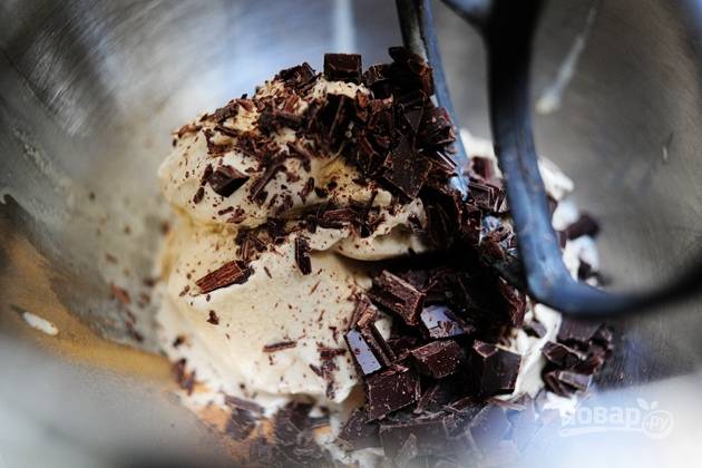 3. Большим и острым ножом измельчите шоколад на небольшие кусочки. Отправьте его в емкость с мороженым, добавьте к нему корицу, мускатный орех и перемешайте до однородности.