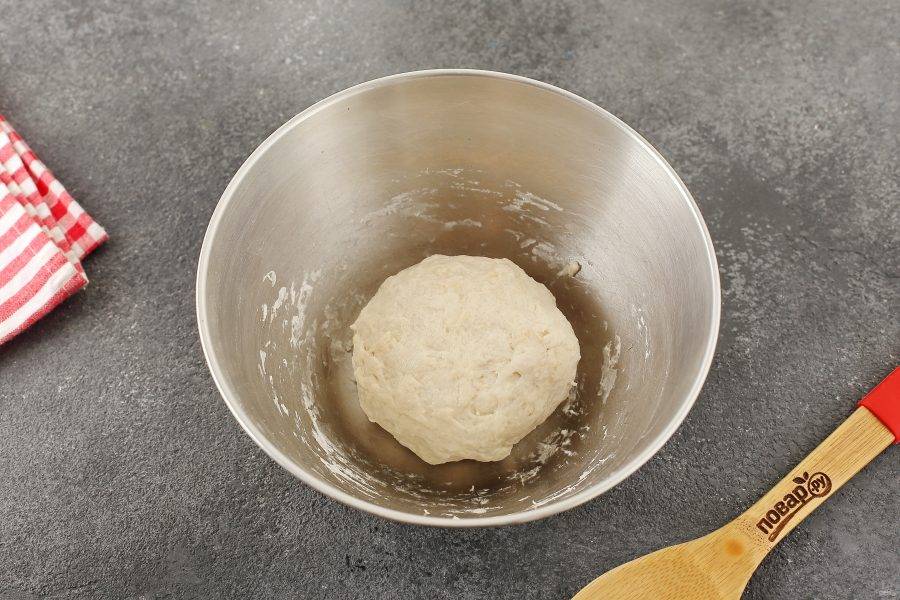 Далее руками, замесите мягкое, чуть липкое тесто. Соберите его в шар, смажьте маслом, накрой миску пищевой пленкой и оставьте тесто на 1,5 часа. Оно должно увеличиться в размере.