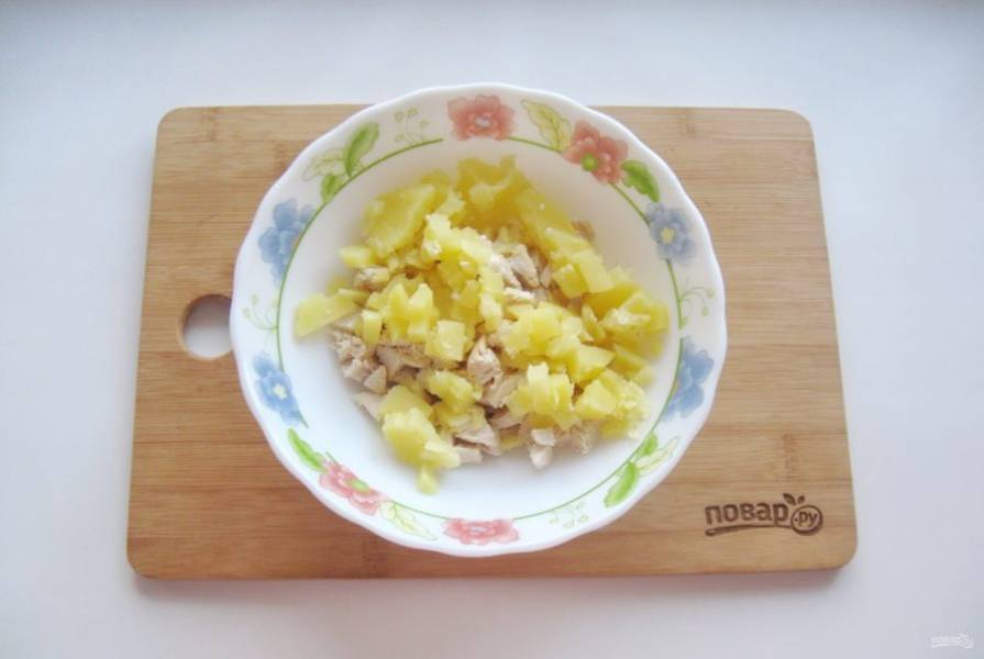 Картофель сварите, охладите, очистите и мелко нарежьте, выложите в салатник с курицей.