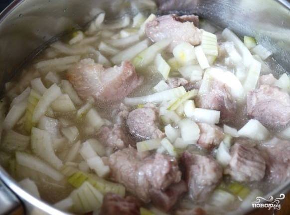 Тем временем почистите и нарежьте лук. Добавьте его к кусочкам мяса. Тушите все вместе под крышкой 45 минут.