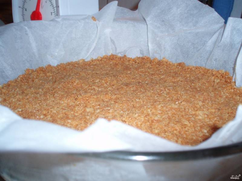 1. Печенье перетираем в крошку вместе с растопленным сливочным маслом. Выкладываем эту массу на дно формы, утрамбовывая. 