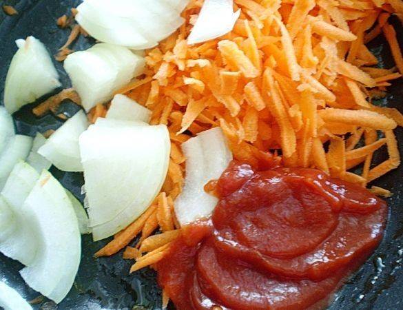 Теперь приступим к подготовке соуса, в котором будем тушить перцы. На растительном масле обжариваем минут 5 лук, нарезанный полукольцами, оставшуюся натертую морковь и томатную пасту.