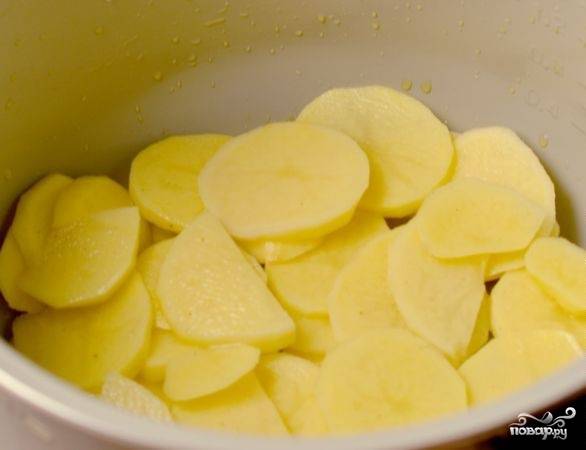 5. На дно мультиварки налить немного растительного масла. Можно воспользоваться кисточкой или обычным бинтиком, чтобы хорошо промазать не только дно, но и стенки. Выложить треть картофеля на дно.