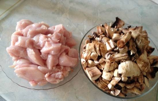 Подготовим ингредиенты. Промойте мясо и грибы. Порежьте филе небольшими кусками. Шампиньоны режем более крупно.
