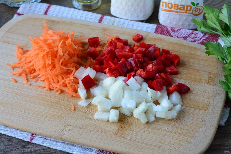 Подготовьте овощи для зажарки. Почистите лук, морковку и сладкий перец. Нарежьте кубиками лук и перец, а морковь натрите на терке.