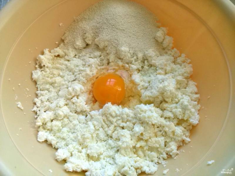 Творог разомните вилкой, добавьте яйцо, манку, по желанию 1 ч.л. сахара, замесите тесто.