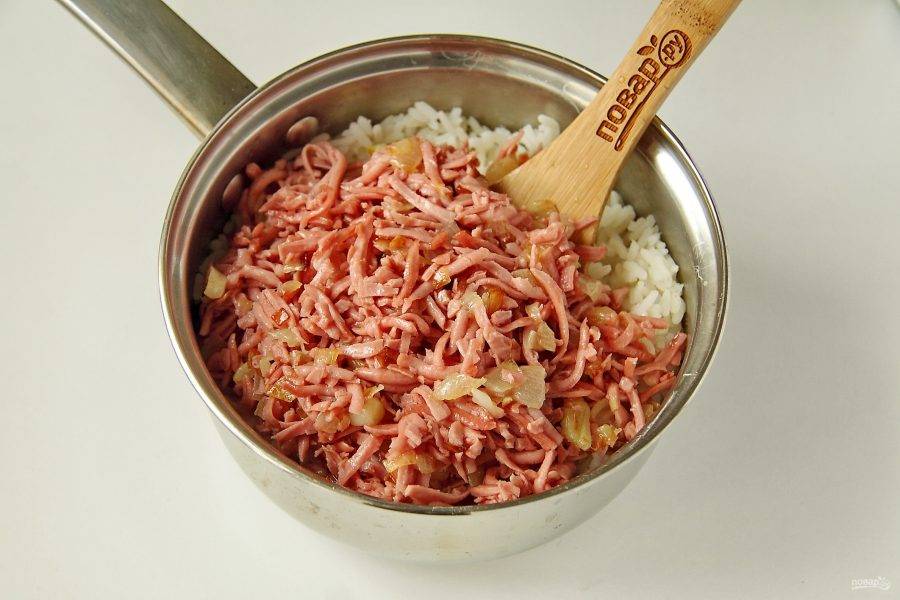 Колбасу натрите на терке. Лук нарежьте кубиками. Обжарьте лук с колбасой на сковороде до готовности и добавьте к рису.