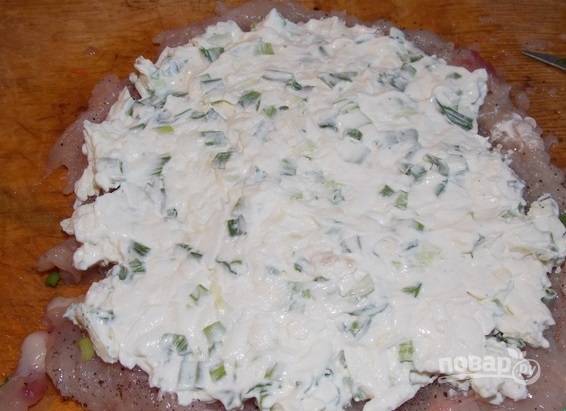 3. Для начинки натрите на терке плавленый сыр, соедините его со сметаной или майонезом и перемешайте. Добавьте пропущенный через пресс чеснок и зелень. Распределите начинку ровным слоем на филе. 