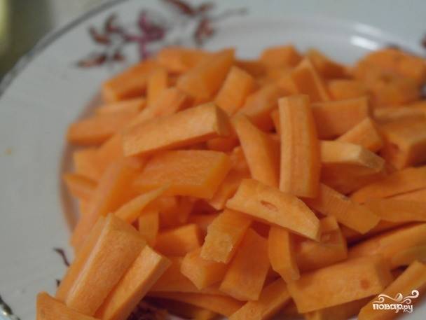 Морковь очистите и вымойте. Нарежьте ее соломкой. Если вы хотите сделать это быстрее, можете использовать вместо ножа терку. Выложите морковь к луку на сковородку.