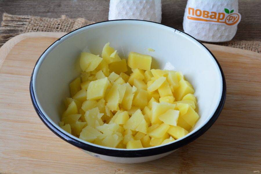 Сварите картофель до мягкости, остудите и нарежьте кубиками. Выложите в глубокую емкость.