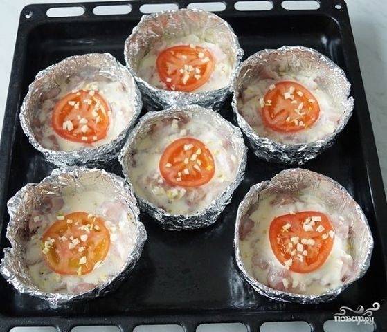 Помидоры помойте и нарежьте кружками. Уложите их по порциям. Потом измельчите чеснок, который также распределите по формам.