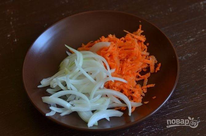 Вымойте и очистите лук с морковкой. Затем лук нарежьте тонкими полукольцами, а морковку натрите на крупной терке. 