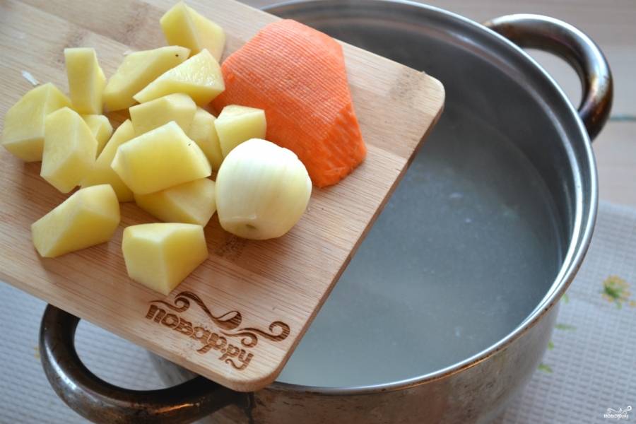 Очищенный картофель порежьте небольшими кусочками и добавьте в бульон. Туда же отправьте целую луковицу и морковку. Ни резать, ни натирать на терке их не нужно, они необходимы только для цвета и аромата, а конце их следует вынуть.