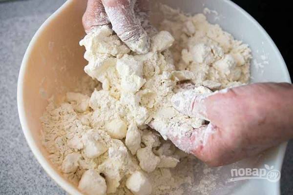 В мучную смесь отправьте размягченное масло, порезанное кубиком. Тесто месите руками до однородной консистенции, которая должна походить на песочное тесто.