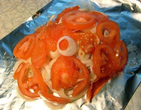 5. Вымыть, обсушить и нарезать кольцами помидоры. Распределить сверху лука по всей поверхности. При желании дополнить этот простой рецепт куриной грудки в фольге в духовке можно и другими овощами по вкусу.
