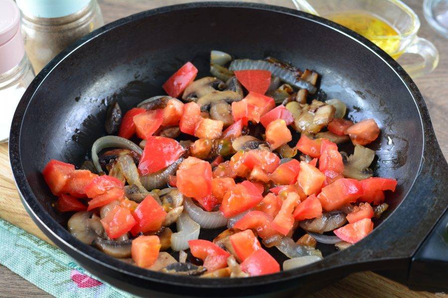 Нарежьте кубиками помидоры и сразу всыпьте к грибам, перемешайте.