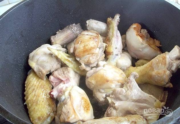 В глубокой сковороде разогреваем масло. Выкладываем части курицы, обжариваем птицу до легкой золотистой корочки на среднем огне.