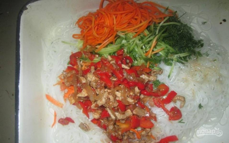 Выложите содержимое сковородки вместе с маслом к отваренной фунчозе. Огурец вымойте и нарежьте соломкой, зелень порубите, посолите и поперчите. Добавьте корейскую морковь и тщательно перемешайте. 