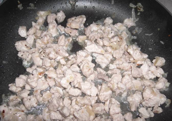 Как только лук приобретёт золотистый цвет, добавьте к нему нарезанную свинину. Обжаривайте до готовности мяса (минут 15).