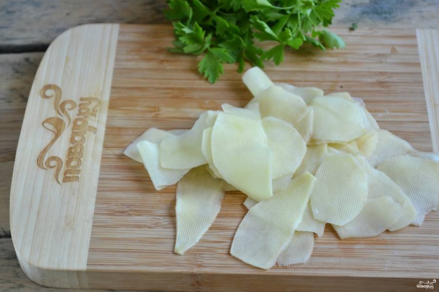С помощью овощечистки или специального ножа для чипсов порежьте картофель на тончайшие слайсы. 