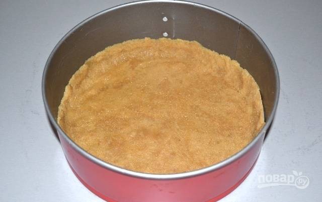 На дно разъемной формы для выпечки (d=22 см) положите круг из пергаментной бумаги, выложите смесь печенья с маслом, утрамбуйте и поставьте в холодильник на 30 минут.