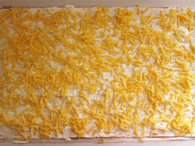 Ровным слоем распределите по лавашу тертый сыр.