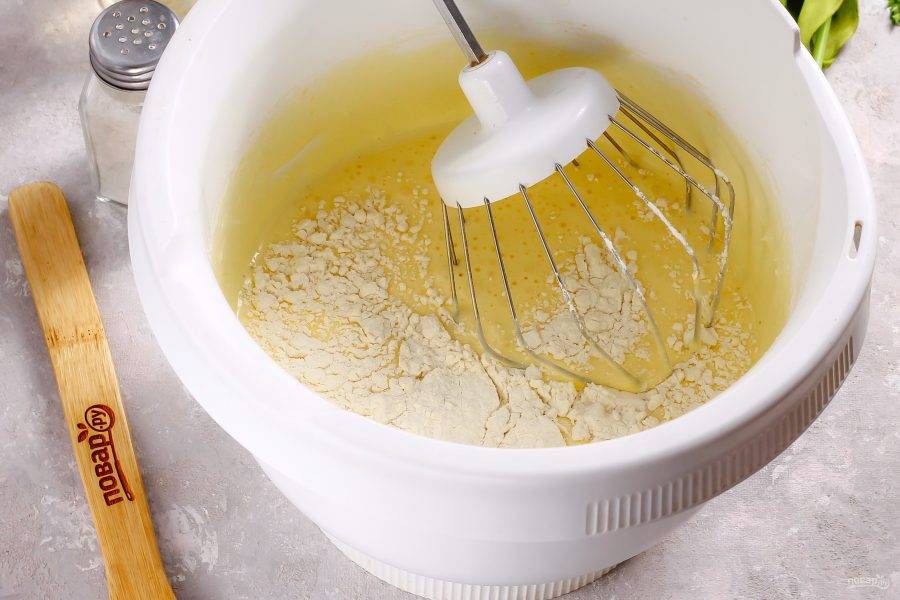 Добавьте пшеничную муку и разрыхлитель. Аккуратными движениями вмешайте муку в яичную массу, но не взбивайте. Прогрейте духовку до 180 градусов и смажьте форму маслом.