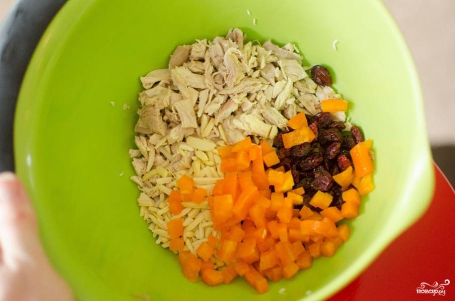 Очистите от семян болгарский перец. Нарежьте его небольшими кусочками, так же порежьте варёное куриное филе. Смешайте их, добавьте клюкву.