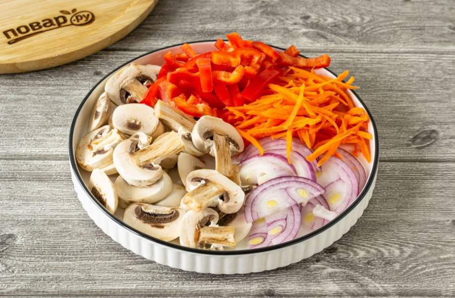 Нарежьте лук полукольцами, морковь нашинкуйте соломкой, у перца удалите сердцевину и тоже нарежьте соломкой. Шампиньоны помойте и нарежьте пластинками.