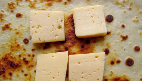 3. По центру каждого блина выкладываем несколько кусочков сыра, сворачиваем блин тугим конвертиком.