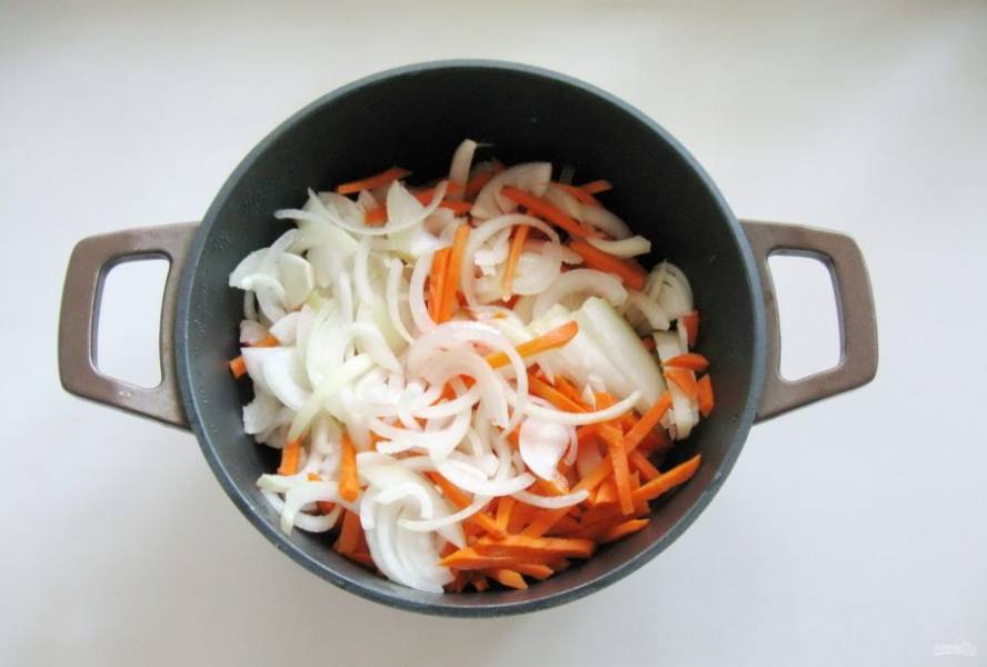 Лук и морковь очистите, помойте и нарежьте. Лук полукольцами, а морковь соломкой. Добавьте в кастрюлю к мясу. Налейте еще немного масла и тушите курицу с овощами 10-15 минут, перемешивая.