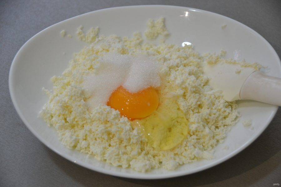 Добавьте в творог яйцо, сахарный песок и щепотку соли.