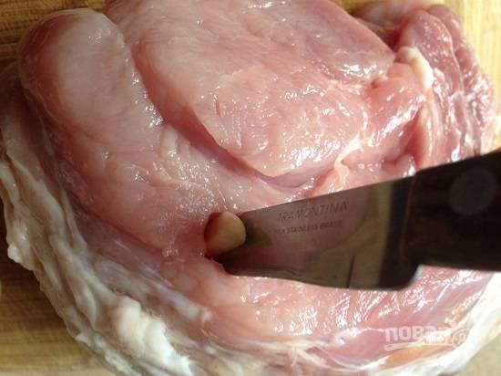 Затем нашпигуем мясо со всех сторон чесноком. Протыкаем мясо ножом и вставляем в отверстие кусочек чеснока.