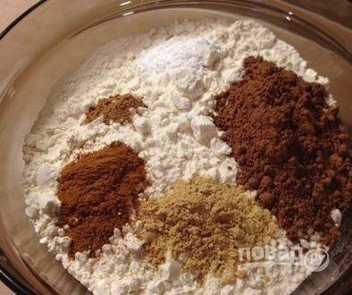 Муку просейте через сито, добавьте ее к масляной смеси. Также высыпьте в миску какао-порошок, молотый сухой имбирь, корицу и мускатный орех. 