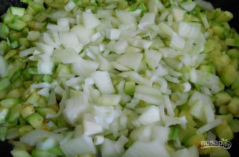 Кабачки кубиками обжарьте в горячем масле 5 минут, присолив. Затем добавьте к ним нарезанный лук. Готовьте овощи ещё 3 минуты, помешивая.