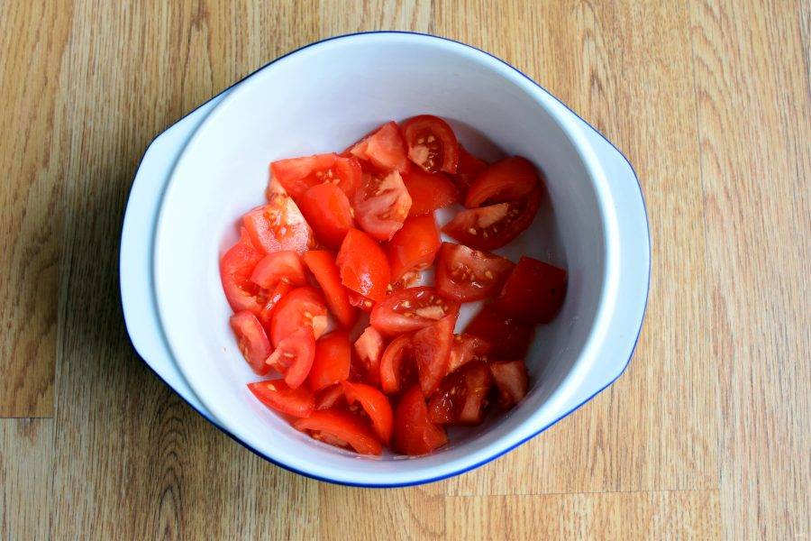  Плотные помидоры нарежьте крупными дольками и выложите в глубокую миску.