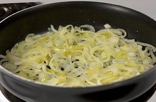 4. На отдельную сковороду налить немного растительного масла. Очистить луковицу и нарезать тонкими полукольцами. Отправить лук на сковороду и обжарить немного до слегка золотистого оттенка. 