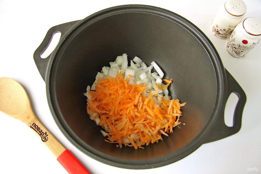 Лук нарежьте кубиками. Морковь натрите на крупной терке. Переложите овощи в сковороду (казанок) и добавьте масло.