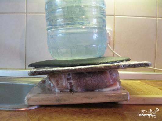 Закрываем крышкой, а лучше придавливаем тарелкой и убираем в холодильник на трое суток. Каждый день, утром и вечером, переворачиваем мясо в рассоле, чтобы все равномерно просаливалось. Через три дня мясо нужно положить под пресс, чтобы с него стекла вода. Перед этим и после оботрите куски бумажными полотенцами.