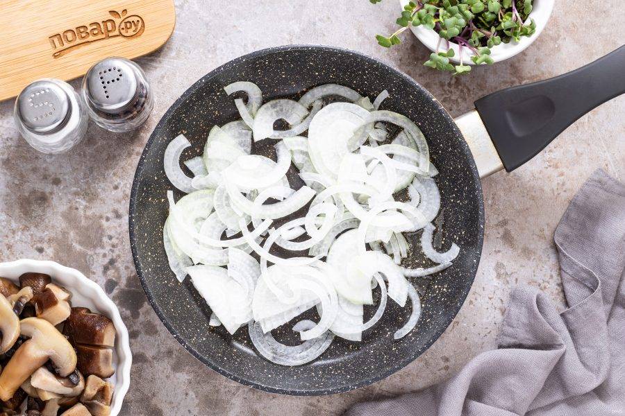 Репчатый лук нарежьте полукольцами. Разогрейте сковороду на среднем огне и обжарьте репчатый лук до мягкости и прозрачности.