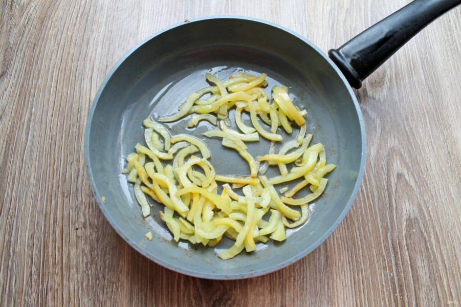 Болгарский перец очистите от семян и плодоножки, порежьте соломкой. В сковороду налейте растительное масло, разогрейте и выложите перец. Обжаривайте его на среднем огне, перемешивая, в течение 4 минут, переложите в тарелку.