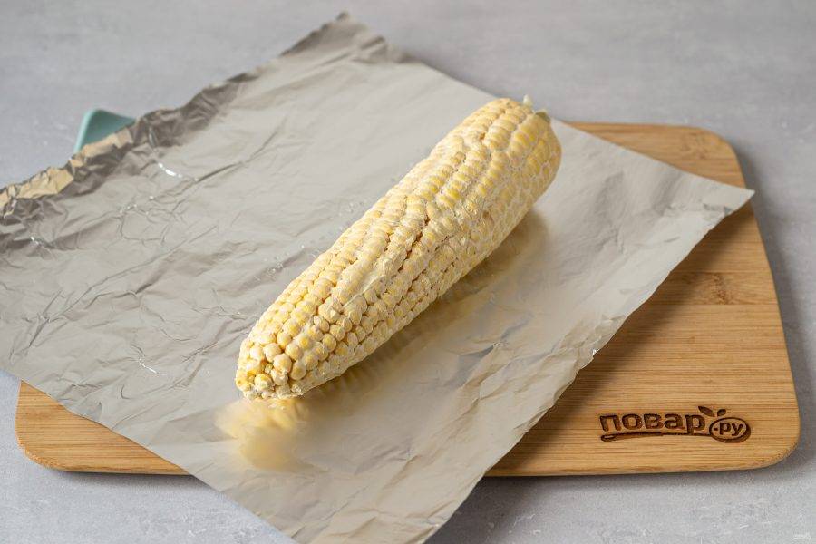 Выложите кукурузу на фольгу, натрите сливочным маслом со всех сторон.